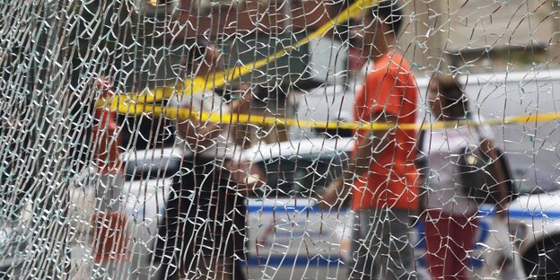 Eine durch die Explosion stark beschädigte Fensterscheibe in Manhattan, im Hintergrund Fußgänger Eine durch die Explosion stark beschädigte Fensterscheibe in Manhattan, im Hintergrund Fußgänger
