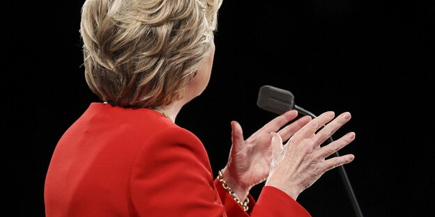 Der Rücken einer Frau mit roter Jacke. Es ist Hillary Clinton Der Rücken einer Frau mit roter Jacke. Es ist Hillary Clinton