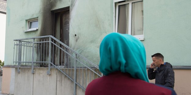 eine Frau mit Kopftuch vor der russgeschwärzten Moschee eine Frau mit Kopftuch vor der russgeschwärzten Moschee