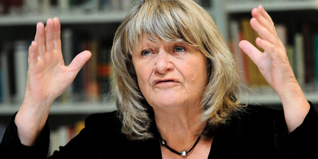 Frauenrechtlerin Alice Schwarzer steht mit erhobenen Händen vor einem Bücherregal Frauenrechtlerin Alice Schwarzer steht mit erhobenen Händen vor einem Bücherregal