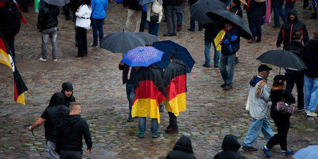 Menschen mit Deutschlandfahnen und Regenschirmen Menschen mit Deutschlandfahnen und Regenschirmen