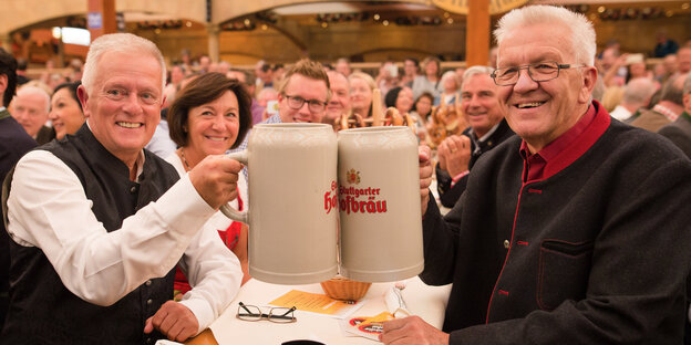 Fritz Kuhn und Winfried Kretschmann stoßen mit riesigen Bierkrügen an