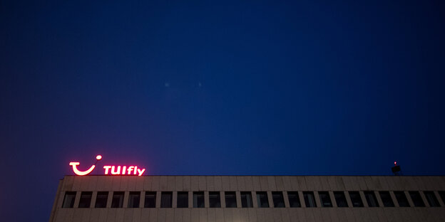 Rot leuchtendes Tuifly-Logo auf einem mehrstöckigen Haus bei Nacht