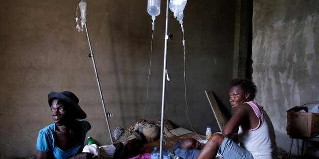 Zwei Frauen sitzen bei ihren Kindern, die Infusionen bekommen Zwei Frauen sitzen bei ihren Kindern, die Infusionen bekommen