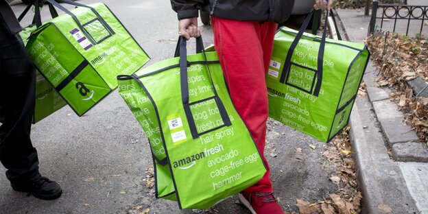 Zwei Menschen tragen neon-grüne Taschen von Amazon Zwei Menschen tragen neon-grüne Taschen von Amazon