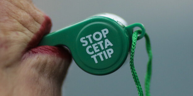 Eine Frau hält im Mund eine Trillerpfeife. Darauf steht „Stopp Ceta TTIP“ Eine Frau hält im Mund eine Trillerpfeife. Darauf steht „Stopp Ceta TTIP“