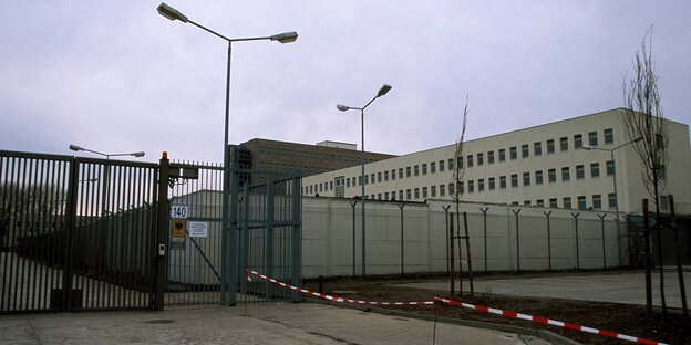 Ein Plattenbau hinter hohem Zaun Ein Plattenbau hinter hohem Zaun