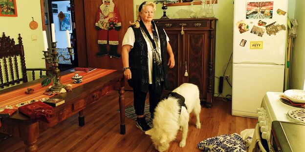 Eine Frau steht neben einem weißen Hund in einem Wohnzimmer Eine Frau steht neben einem weißen Hund in einem Wohnzimmer
