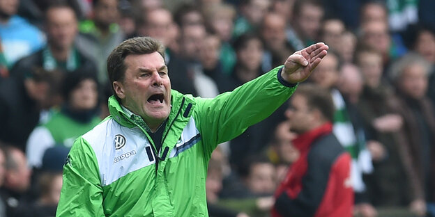 Mann in grüner Jacke schreit und hebt den Arm Mann in grüner Jacke schreit und hebt den Arm
