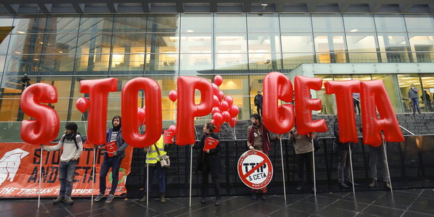 große Buchstaben "Stop Ceta" vor einem Gebäude mit viel Glas große Buchstaben "Stop Ceta" vor einem Gebäude mit viel Glas