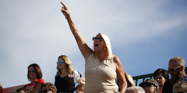 Eine Frau ragt aus einer Gruppe Trump-Anhänger heraus - und reckt den rechten Arm nach oben Eine Frau ragt aus einer Gruppe Trump-Anhänger heraus - und reckt den rechten Arm nach oben