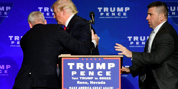 Zwei Sicherheitsleute bringen Donald Trump von der Bühne Zwei Sicherheitsleute bringen Donald Trump von der Bühne