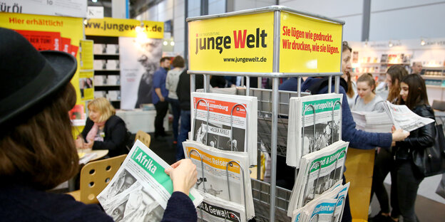 Eine Frau nimmt sich eine Zeitung aus einem Zeitungshalter der „jungen Welt“