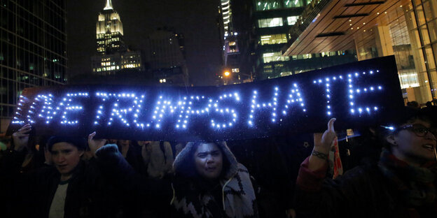 Menschen protestieren in New York mit dem leuchtenden Schriftzug "Love Trumps Hate" nach der Wahl Donald Trumps zum US-Präsidenten Menschen protestieren in New York mit dem leuchtenden Schriftzug "Love Trumps Hate" nach der Wahl Donald Trumps zum US-Präsidenten