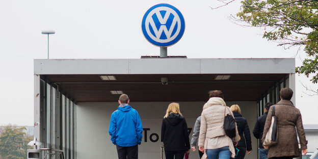 Menschen von hinten, sie gehen auf ein Volkswagen-Logo zu Menschen von hinten, sie gehen auf ein Volkswagen-Logo zu