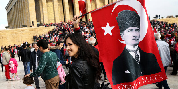 Eine Frau hält eine Flagge mit einem Bild von Atatürk