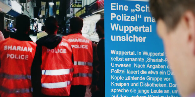 Drei Männer mit dem Rücken zur Kamera. Alle tragen sie Warnwesten mit der Aufschrift „Scharia-Polizei“ Drei Männer mit dem Rücken zur Kamera. Alle tragen sie Warnwesten mit der Aufschrift „Scharia-Polizei“