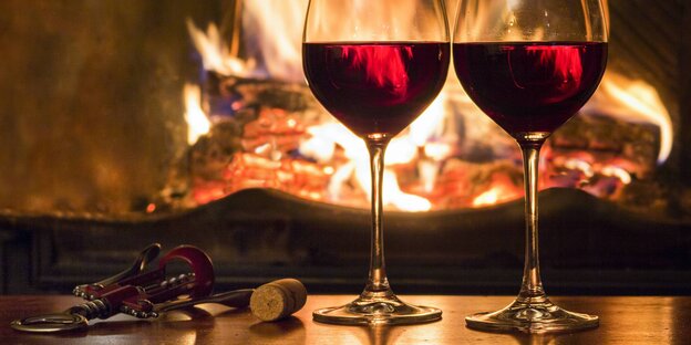 Zwei Gläser mit Rotwein vor einem Kamin Zwei Gläser mit Rotwein vor einem Kamin