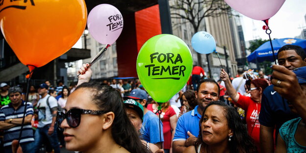 Menschen mit bunten Luftballons auf denen „Fora Temer“ steht Menschen mit bunten Luftballons auf denen „Fora Temer“ steht