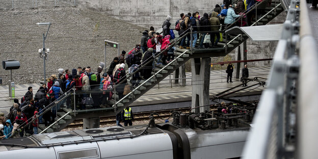 Auf einer Treppe, die von einem Zug wegführt, stauen sich Menschen Auf einer Treppe, die von einem Zug wegführt, stauen sich Menschen