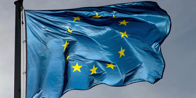Die Flagge der EU weht vor dunkelgrauem Himmel Die Flagge der EU weht vor dunkelgrauem Himmel