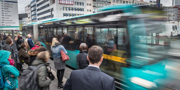 Menschen steigen an einer Haltestelle in einen Bus ein Menschen steigen an einer Haltestelle in einen Bus ein