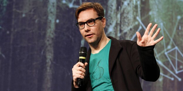 Jacob Appelbaum auf einer Bühne mit einem Mikro Jacob Appelbaum auf einer Bühne mit einem Mikro