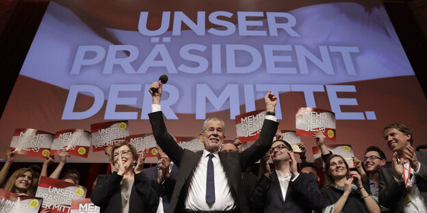 Van der Bellen hebt die Arme zur Siegerpose vor Parteifreunden und einer rot-weiß-roten Projektion an der Wand Van der Bellen hebt die Arme zur Siegerpose vor Parteifreunden und einer rot-weiß-roten Projektion an der Wand