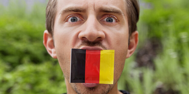 Ein Mann hat eine kleine Deutschlandflagge im offenen Mund Ein Mann hat eine kleine Deutschlandflagge im offenen Mund