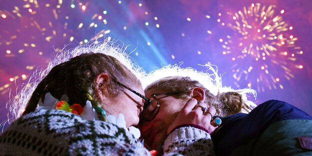 Zwei Menschen küssen sich unter Silvester-Feuerwerk Zwei Menschen küssen sich unter Silvester-Feuerwerk