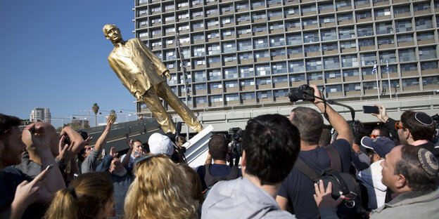 eine Menschenmenge kippt eine goldene Statue eine Menschenmenge kippt eine goldene Statue