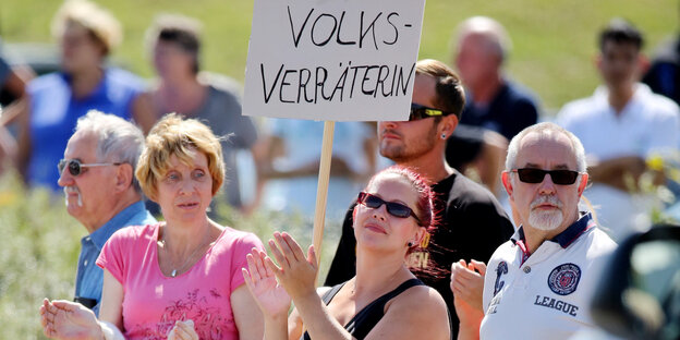 Eine Frau hält ein Schild mit der Aufschrift "Volksverräterin" in einer Menschenmenge Eine Frau hält ein Schild mit der Aufschrift "Volksverräterin" in einer Menschenmenge
