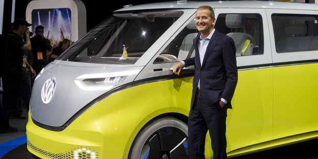 Herbert Diess steht vor einem gelben Elektrobus Herbert Diess steht vor einem gelben Elektrobus