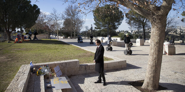 Ein Mann in schwarzem Mantel steht mit gefalteten Händen an der Stelle, an der ein LKW in Jerusalem in eine Gruppe Soldaten fuhr Ein Mann in schwarzem Mantel steht mit gefalteten Händen an der Stelle, an der ein LKW in Jerusalem in eine Gruppe Soldaten fuhr