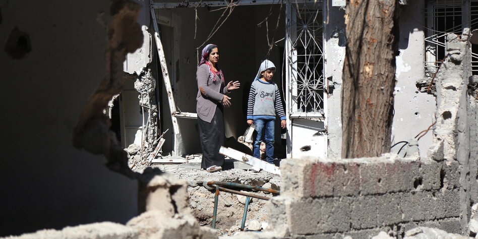Eine Frau und ein Kind stehen vor den Trümmern eines Hauses in der kurdischen Stadt Cizre