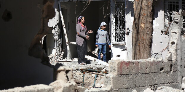 Sokağa çıkma yasaklarının ardından Cizre'de yıkılmış bir evden dışarıya bakan anne ve çocuk