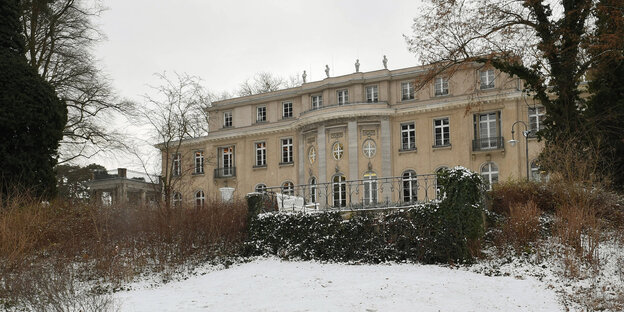 Die Gedenk- und Bildungsstätte Haus der Wannsee-Konferenz erhebt sich zwischen kahlen Bäumen und verschneiten Wiesen Die Gedenk- und Bildungsstätte Haus der Wannsee-Konferenz erhebt sich zwischen kahlen Bäumen und verschneiten Wiesen