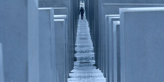 Blick durch die Stelen des Holocaust-Denkmals in Berlin. Im Hintergrund geht ein Mann. Blick durch die Stelen des Holocaust-Denkmals in Berlin. Im Hintergrund geht ein Mann.
