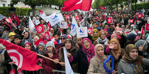 Eine Menschenmenge protestiert mit wehenden Fahnen, meist Nationalflaggen Tunesiens Eine Menschenmenge protestiert mit wehenden Fahnen, meist Nationalflaggen Tunesiens