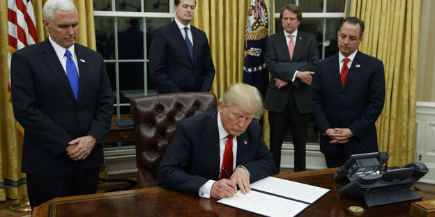 US-Präsident Trump unterschreibt auf einem Blatt Papier US-Präsident Trump unterschreibt auf einem Blatt Papier