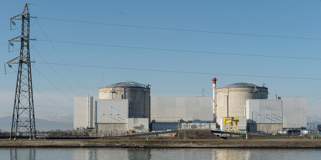 ein Kraftwerk vor blauem Himmel, im Vordergrund Wasser ein Kraftwerk vor blauem Himmel, im Vordergrund Wasser