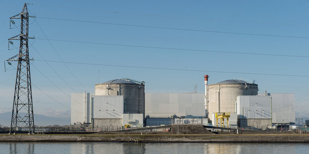 ein Kraftwerk vor blauem Himmel, im Vordergrund Wasser