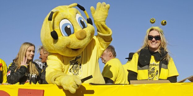Emma, das Maskottchen des BVB neben zwei Fans Emma, das Maskottchen des BVB neben zwei Fans