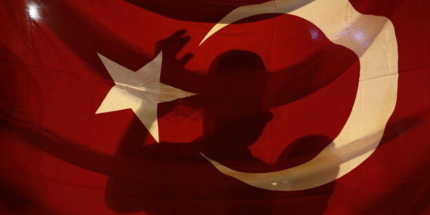 eine türkische Flagge, auf der sich die Silhouette einer Person abzeichnet eine türkische Flagge, auf der sich die Silhouette einer Person abzeichnet