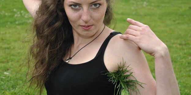 Frau auf Wiese mit Gras unter der Achsel Frau auf Wiese mit Gras unter der Achsel