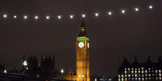 Westminster-Palast bei Nacht, Big Ben ist erleuchtet, eine Lichterkette zieht am Bildrand entlang Westminster-Palast bei Nacht, Big Ben ist erleuchtet, eine Lichterkette zieht am Bildrand entlang