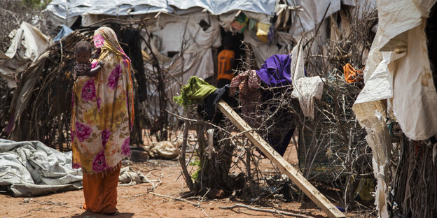 Eine Frau mit Kind steht neben einer Hütte im Flüchtlingslager Dadaab Eine Frau mit Kind steht neben einer Hütte im Flüchtlingslager Dadaab