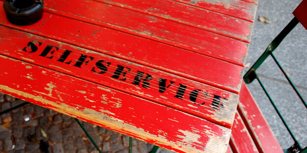 Auf einem Tisch steht ein Aschenbecher und „Selfservice“ Auf einem Tisch steht ein Aschenbecher und „Selfservice“