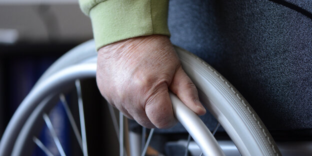 eine Hand am Rad eines Rollstuhls eine Hand am Rad eines Rollstuhls