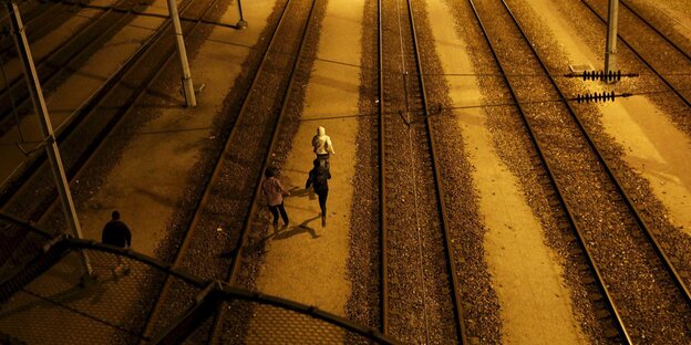 Menschen laufen nachts auf Bahnschienen Menschen laufen nachts auf Bahnschienen
